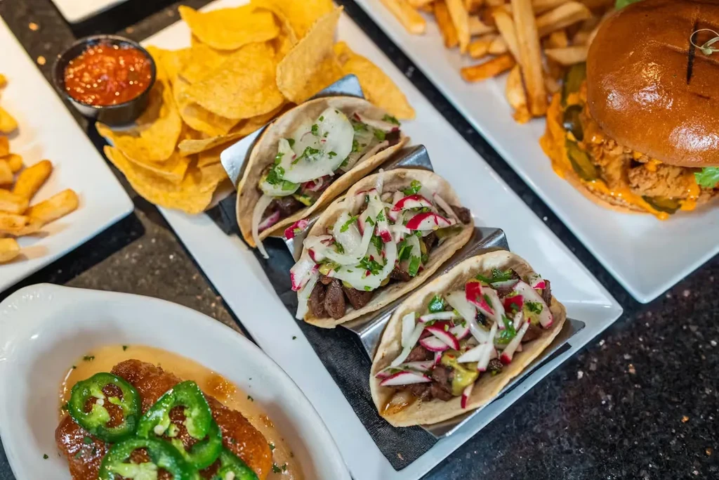 An overhead shot of tacos, nachos, jalapeño poppers, and a burger.