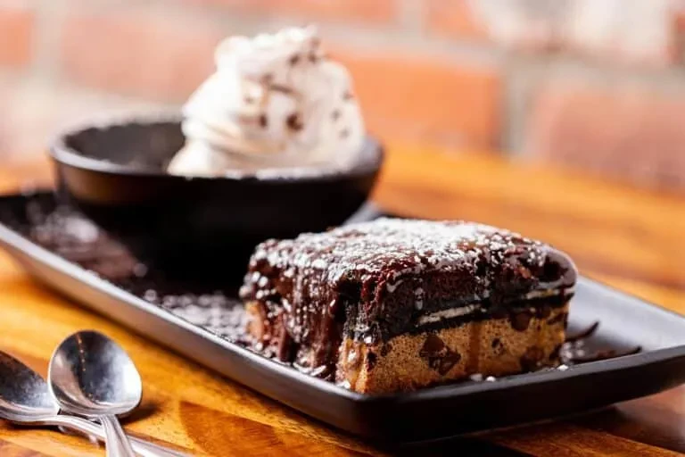 Glossy chocolate dessert bar with ice cream on a black plate.