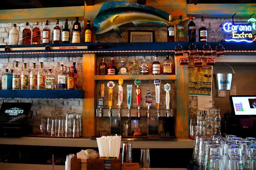 A well-stocked bar with various liquor bottles, beer taps, and glasses.