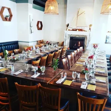 Restaurant dining room set with multiple tables, chairs, and a lit fireplace.