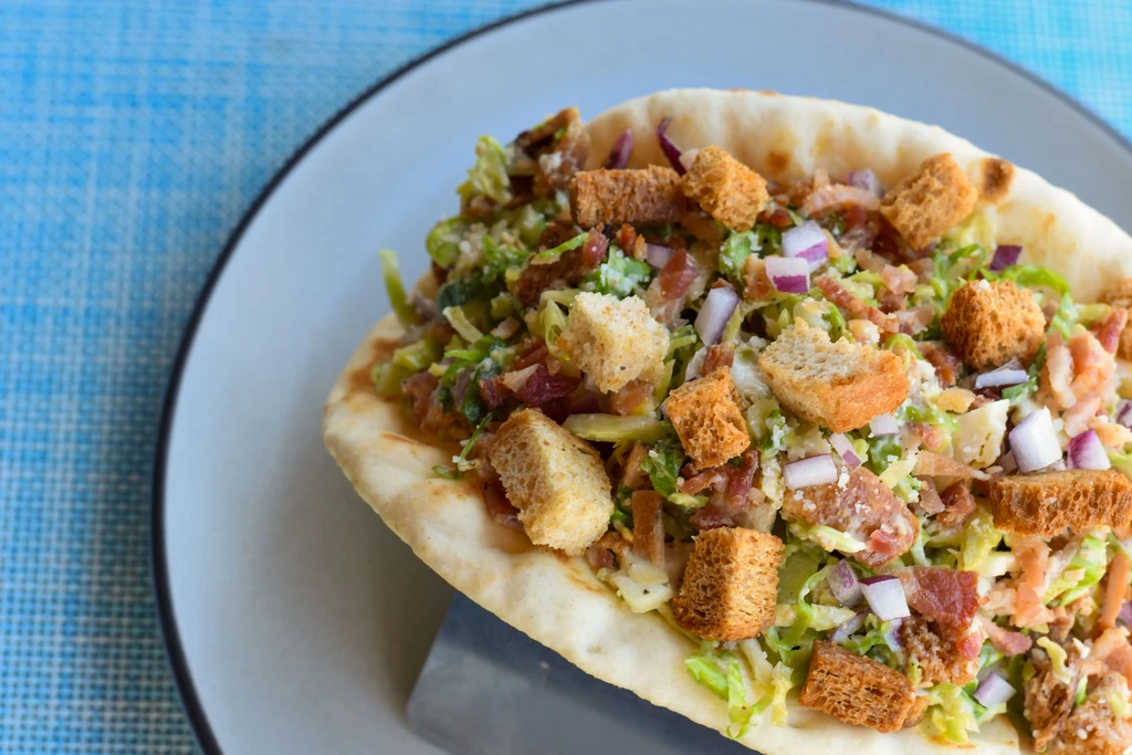 Caesar salad with bacon and croutons on flatbread.