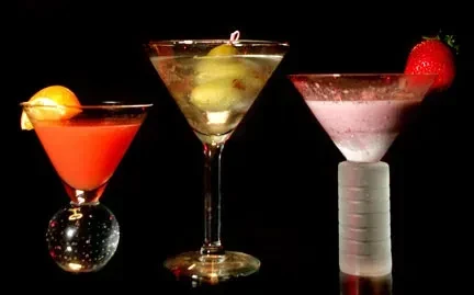 Three martini glasses with different cocktails on a black background.