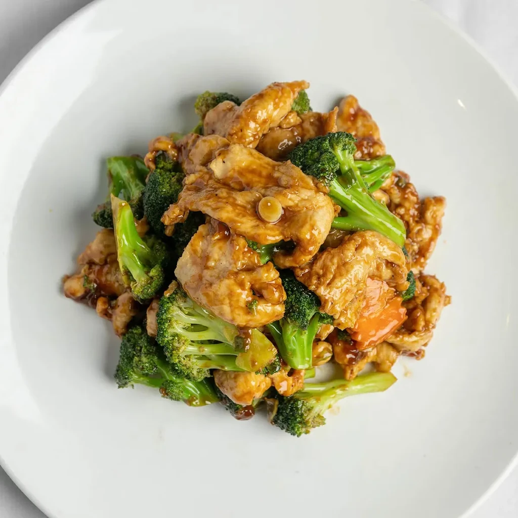 Chicken and broccoli stir-fry on a white plate.
