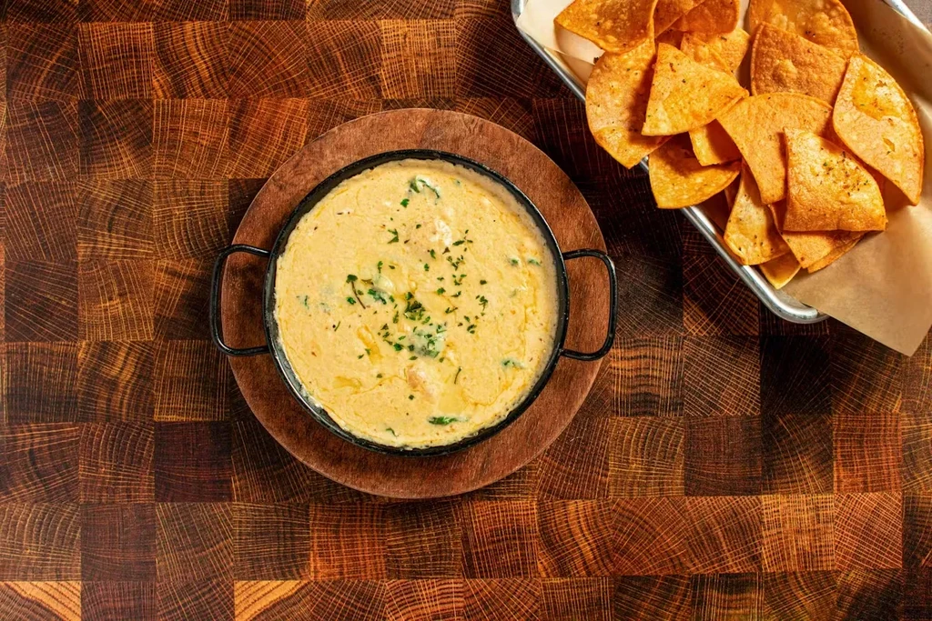 A cast-iron pan of queso dip and a tray of tortilla chips.