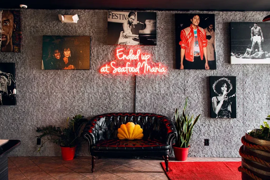 Neon sign "Ended up at Seafood Mania" above a leather couch.