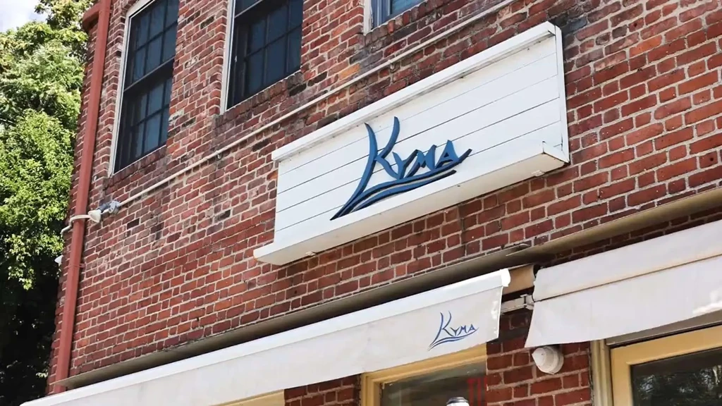Kyma restaurant sign and awning on a brick building.