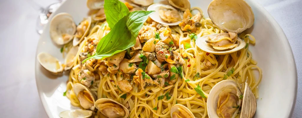 Plate of linguine with clams, parsley, and basil.