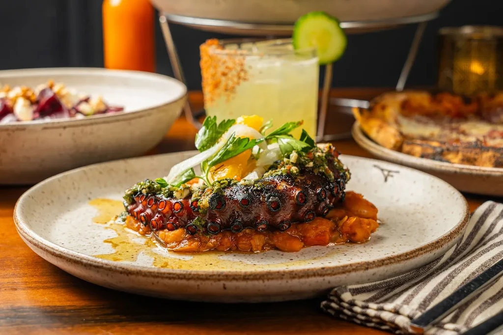Grilled octopus, herbs, and citrus on a bed of beans.