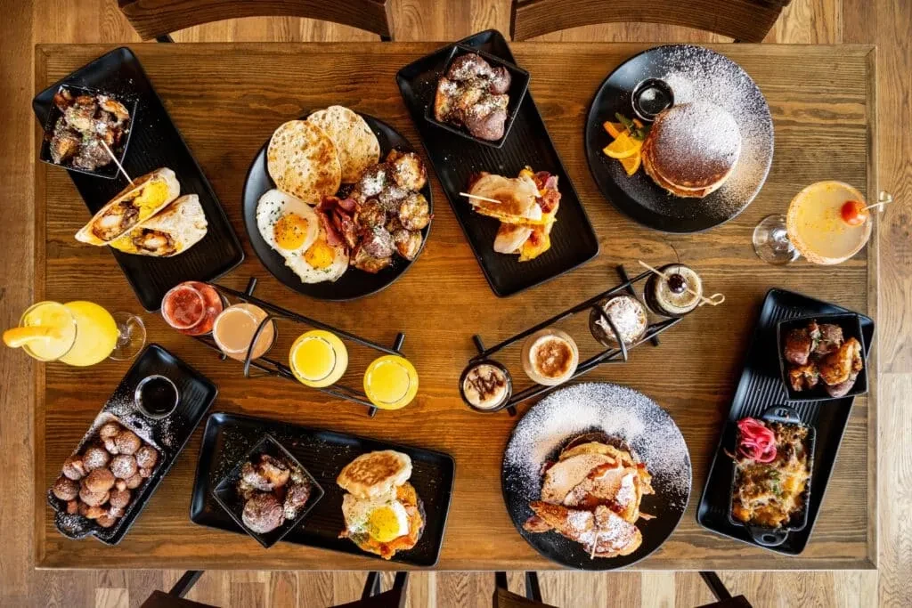 Rustic table laden with various breakfast and brunch dishes and drinks.