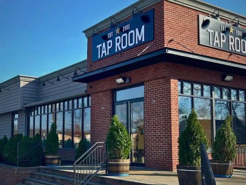 Modern Tap Room with red brick, gray siding, and reflective windows.