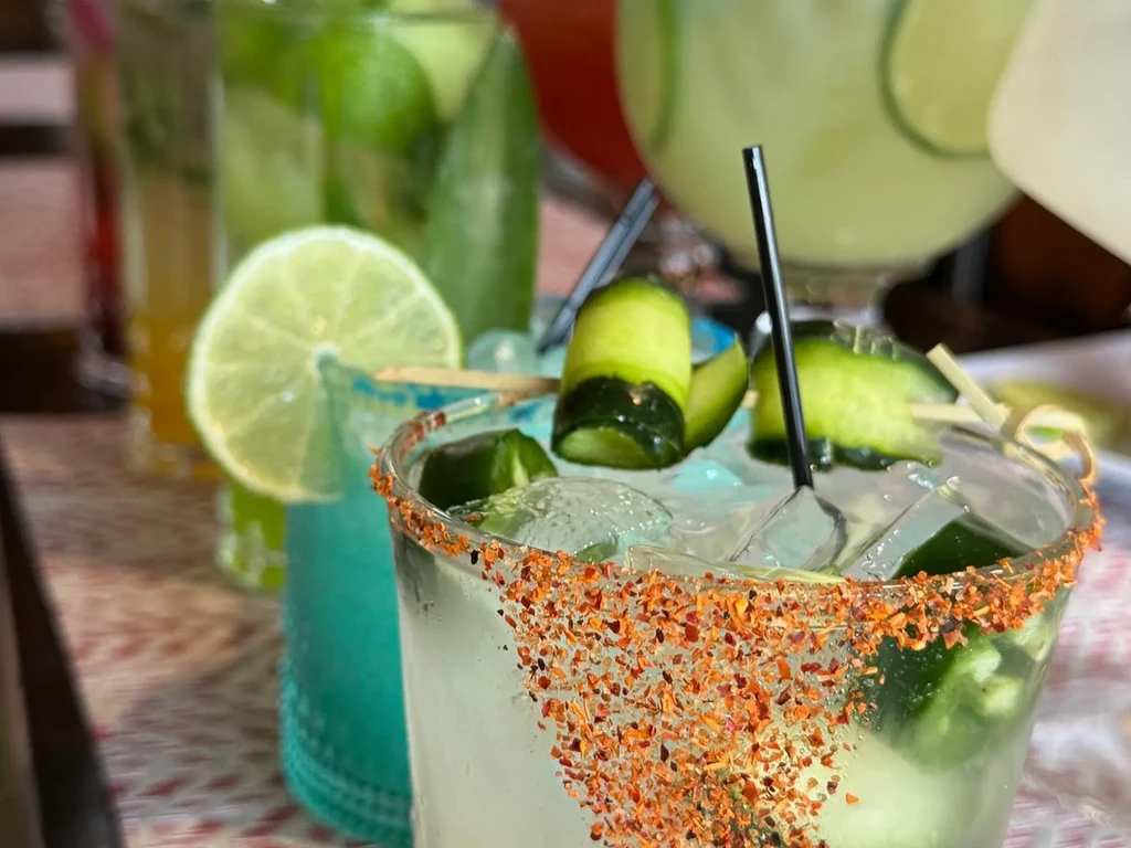 Close-up of four cocktails, one with Tajín, cucumber, and jalapeños.