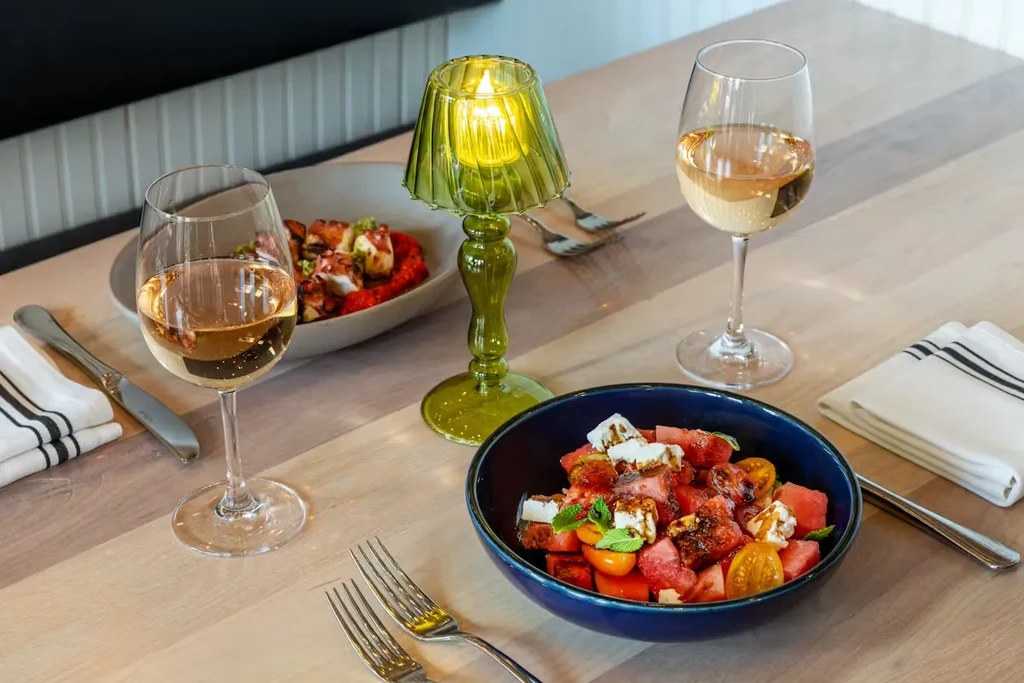 A table set with wine, two entrees, and a glowing green lamp.