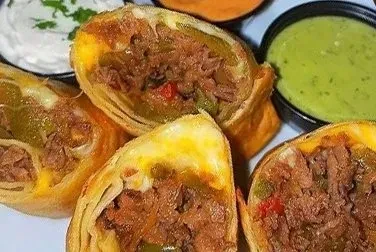Four cut-in-half egg rolls filled with meat, cheese, and vegetables.
