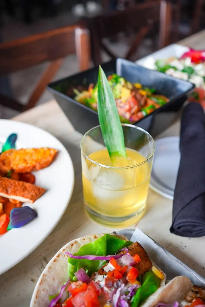 Tacos, fried food, and a cocktail garnished with a pineapple leaf.