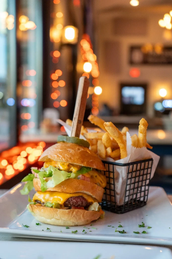 A gourmet double cheeseburger, crinkle-cut fries, and a pickle spear.