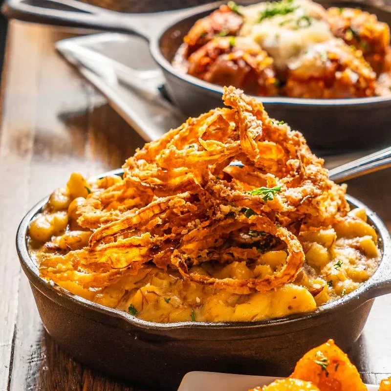 Macaroni and cheese topped with crispy fried onions in a cast iron skillet.