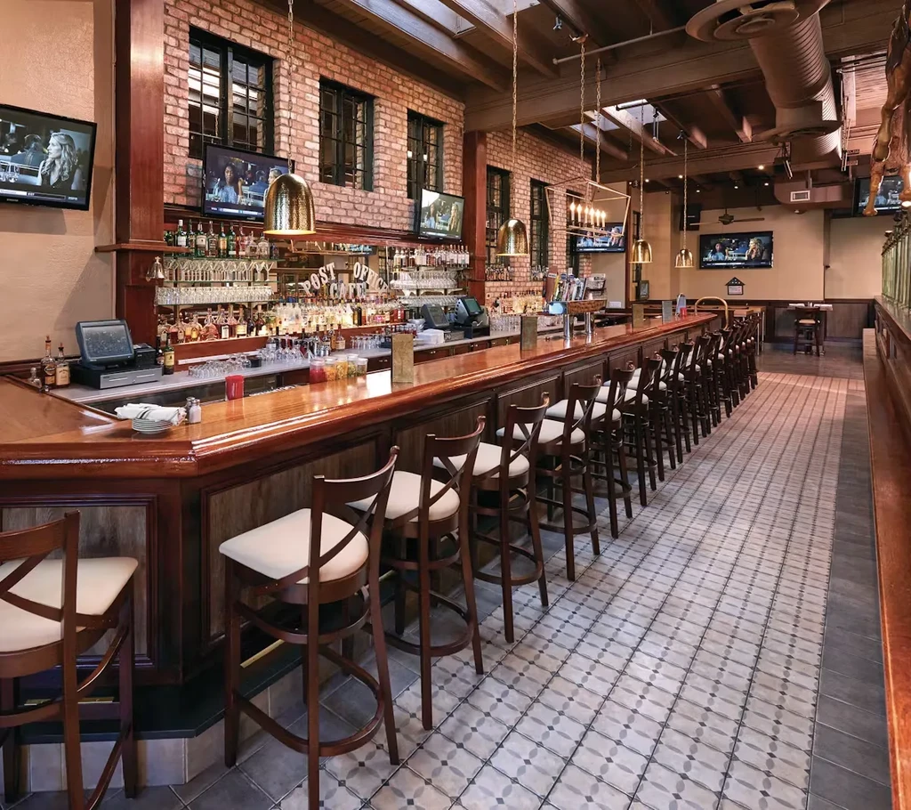 A long, empty wooden bar with rows of high-backed stools.