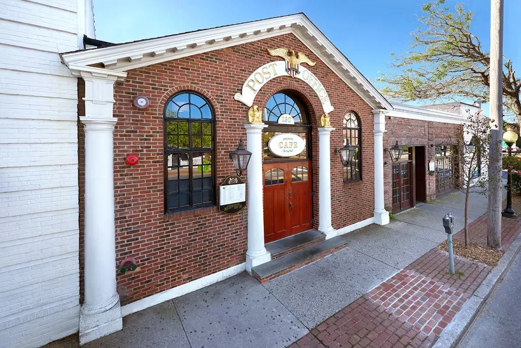 Brick building with "POST OFFICE" sign over its entrance, bright day.
