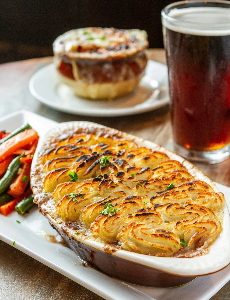 Shepherd's pie with vegetables, French onion soup, and a beer.