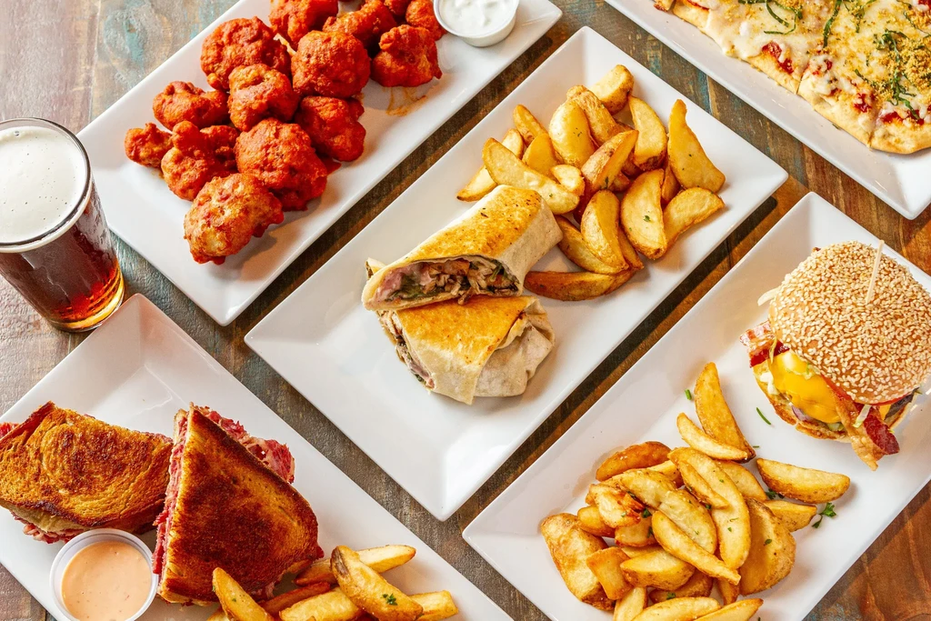 A flat lay of various restaurant dishes on a wooden table.
