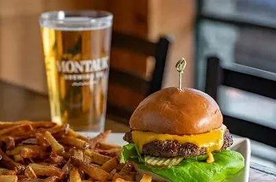 A cheeseburger with fries and a glass of Montauk beer.