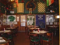 Dining room with sports memorabilia, flags, and framed documents on wooden walls.