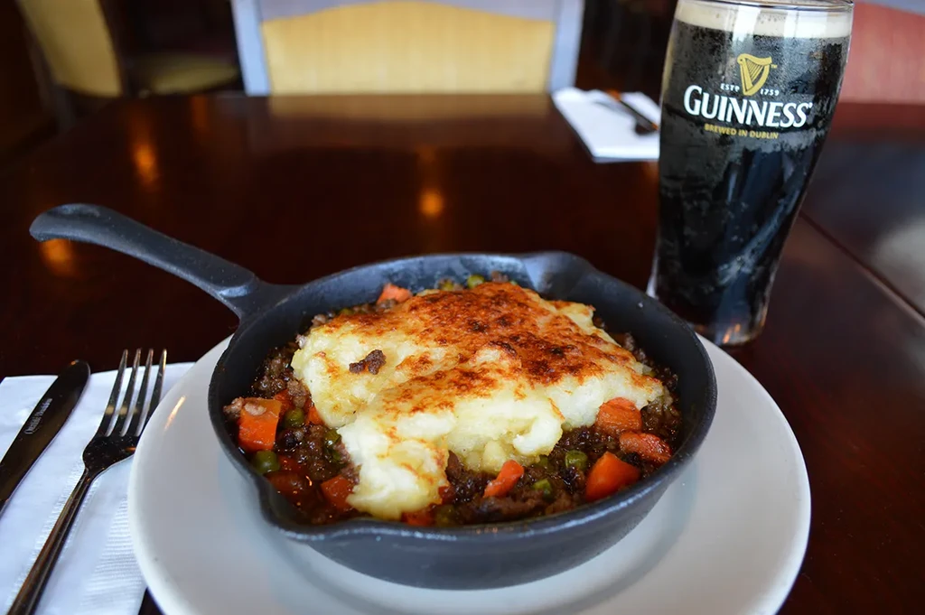 Shepherd's pie in a skillet with a glass of Guinness.