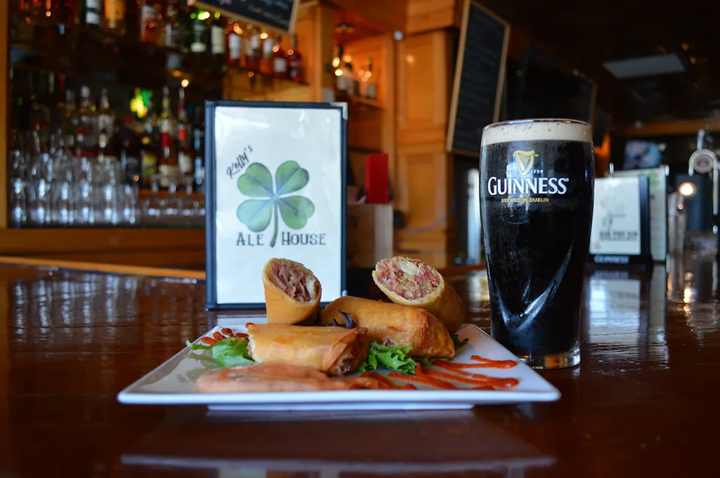 Guinness beer, egg rolls, and Ale House sign on a bar.