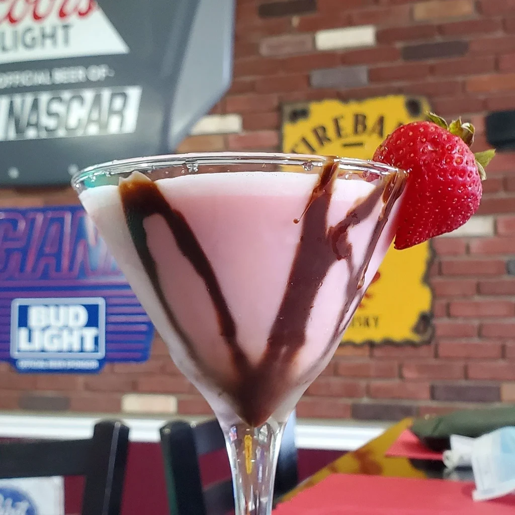 A pink cocktail with chocolate syrup drizzle and a strawberry garnish.