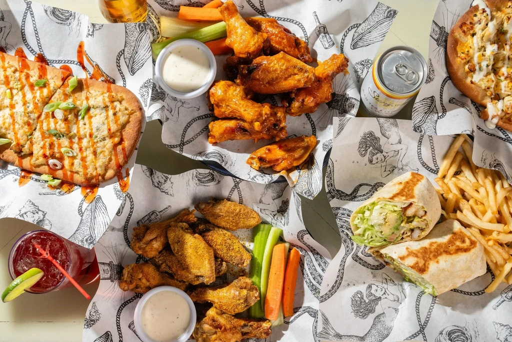 Top-down view of fried foods, drinks, and flatbread on illustrated paper.