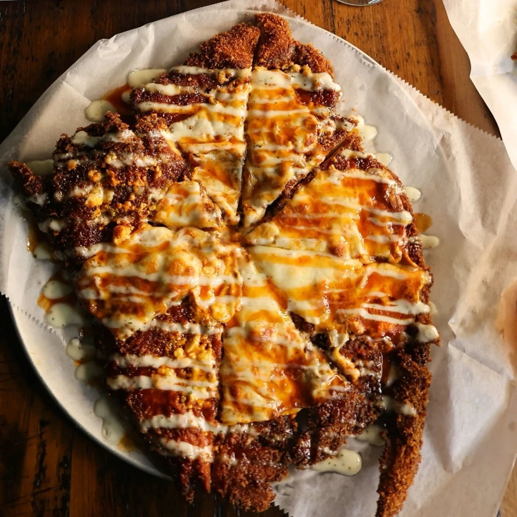 A breaded, sauced, and cheesed cutlet sliced like pizza on a plate.