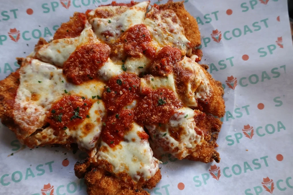 Chicken Parmesan covered in red sauce and melted mozzarella on parchment paper.