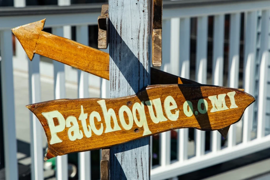 Wooden signs for Patchogue and an arrow pointing left.