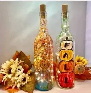 Two corked, lit glass bottles with fall decorations.