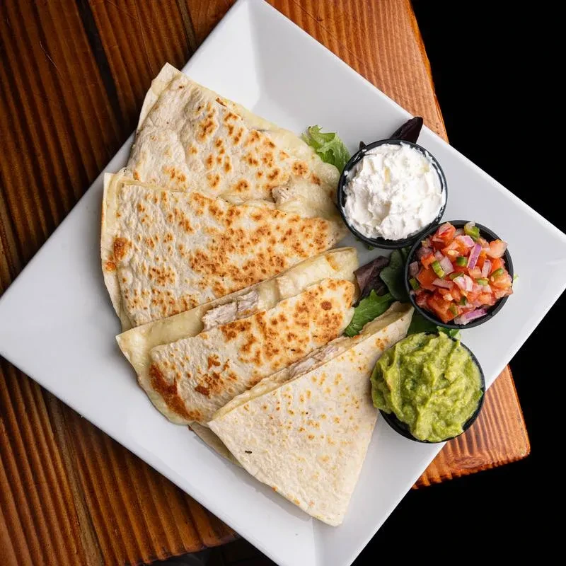Chicken quesadilla wedges with guacamole, pico de gallo, and sour cream.