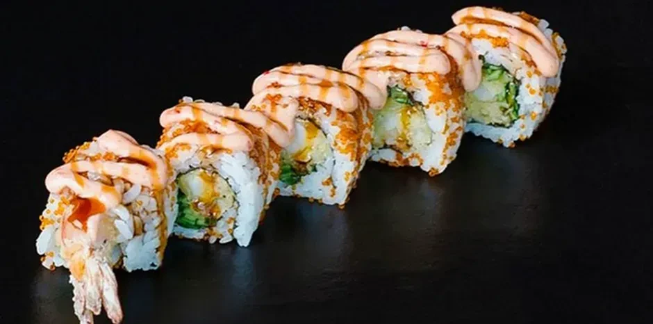 Six sushi rolls with fish roe, sauce, and shrimp tails.