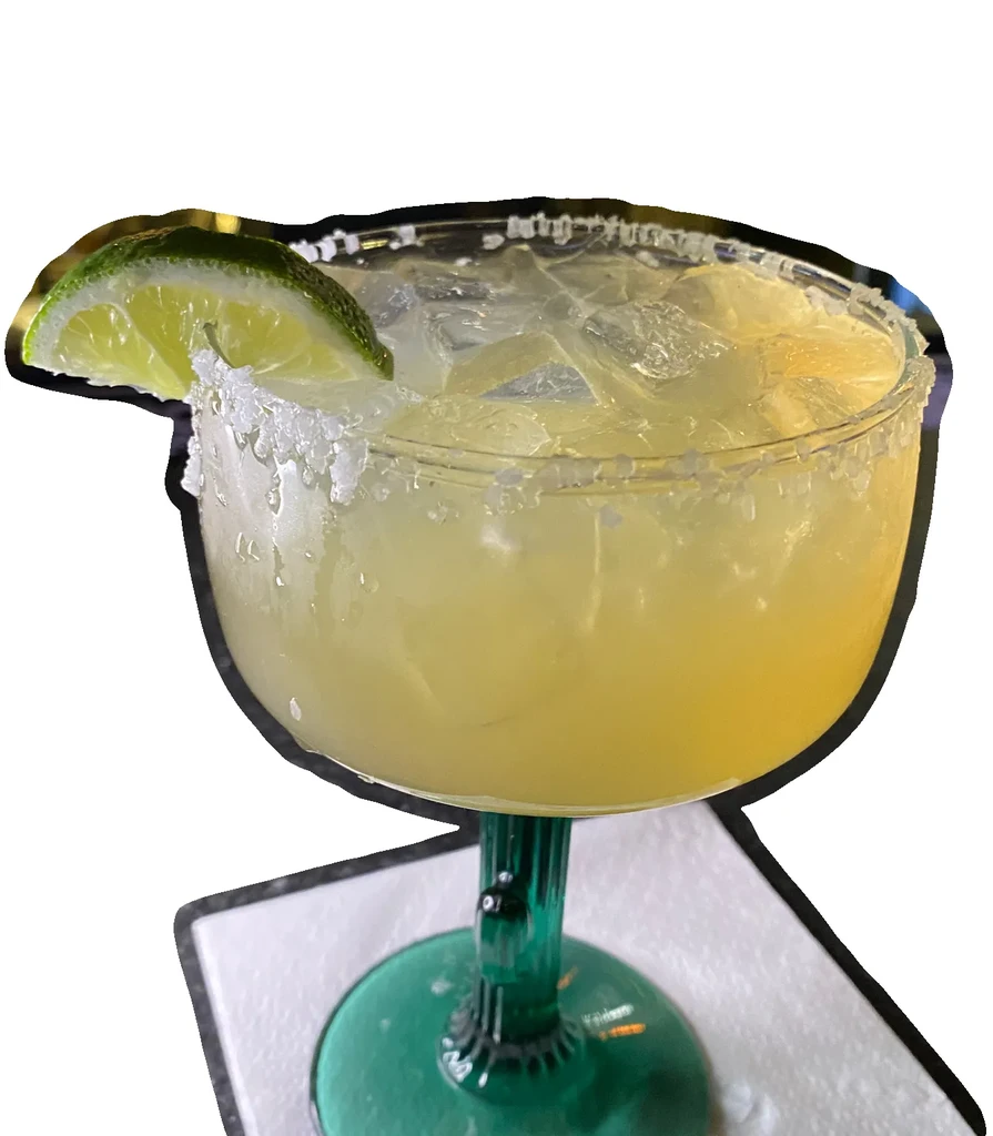 A margarita in a green stemmed glass with a lime wedge and salted rim.