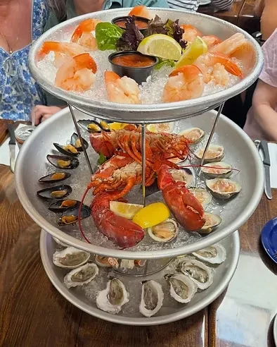 A three-tiered seafood tower with shrimp, lobster, mussels, clams, and oysters.