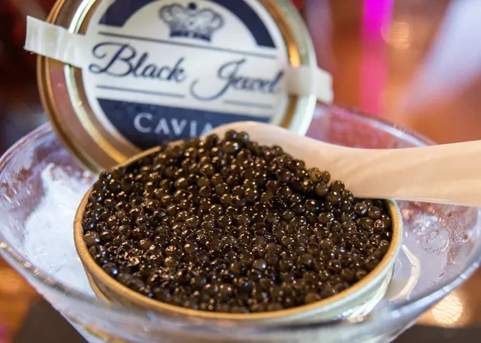 Black Jewel Caviar in a bowl on ice with a wooden spoon.