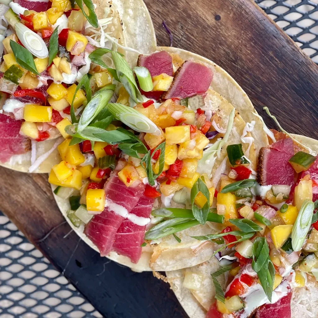 Three seared tuna tacos with mango salsa and green onions.