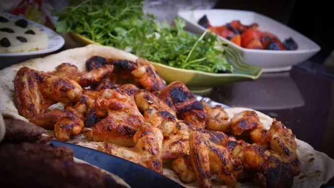 Grilled chicken wings on flatbread with salad and sides.