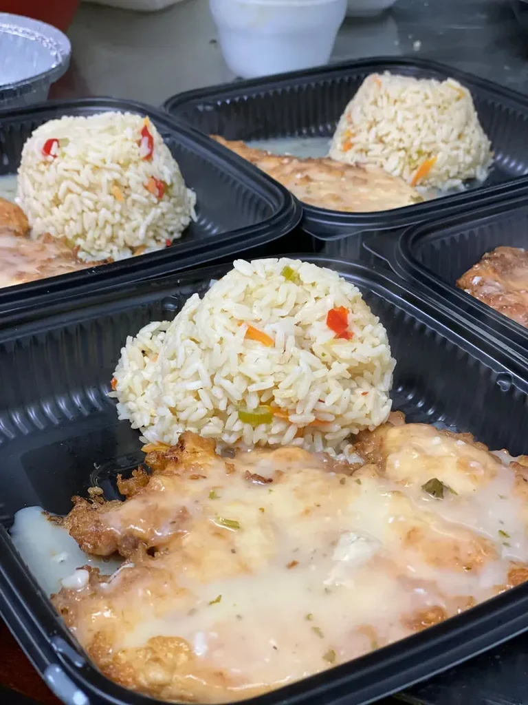 Multiple takeout containers with fried chicken, gravy, and vegetable rice.