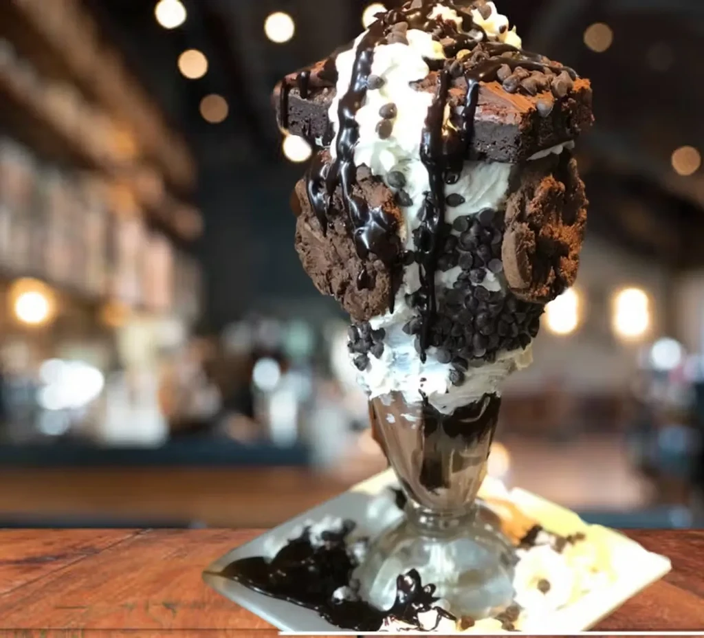 Tall dessert sundae with brownies, whipped cream, and chocolate chips.