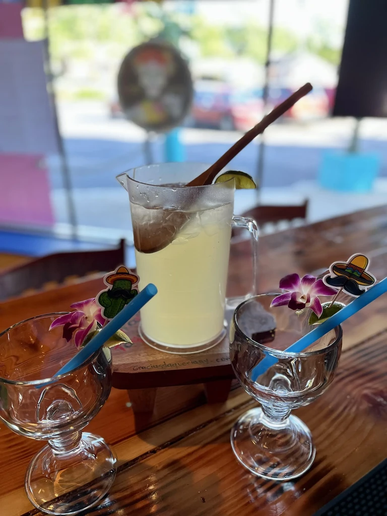 A pitcher of lemonade and two empty glasses with decorative straws.