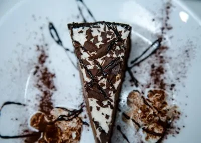 A slice of chocolate cake with white frosting and chocolate shavings.