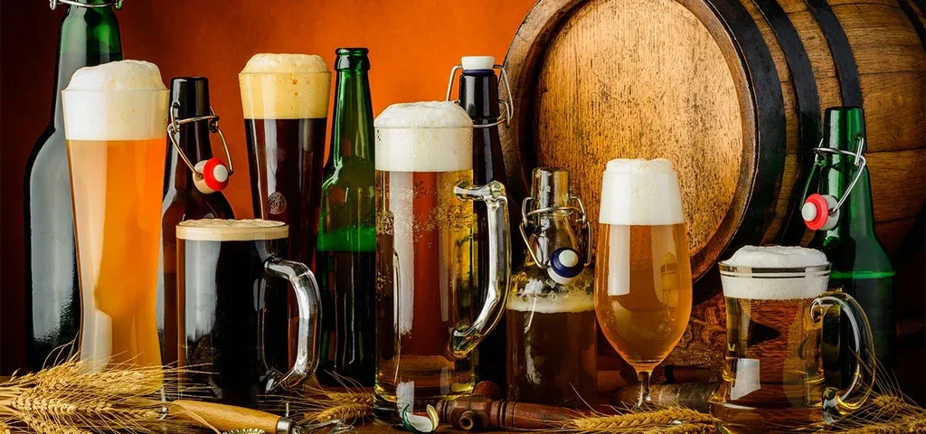 Various types of beer, bottles, and a barrel on a table.
