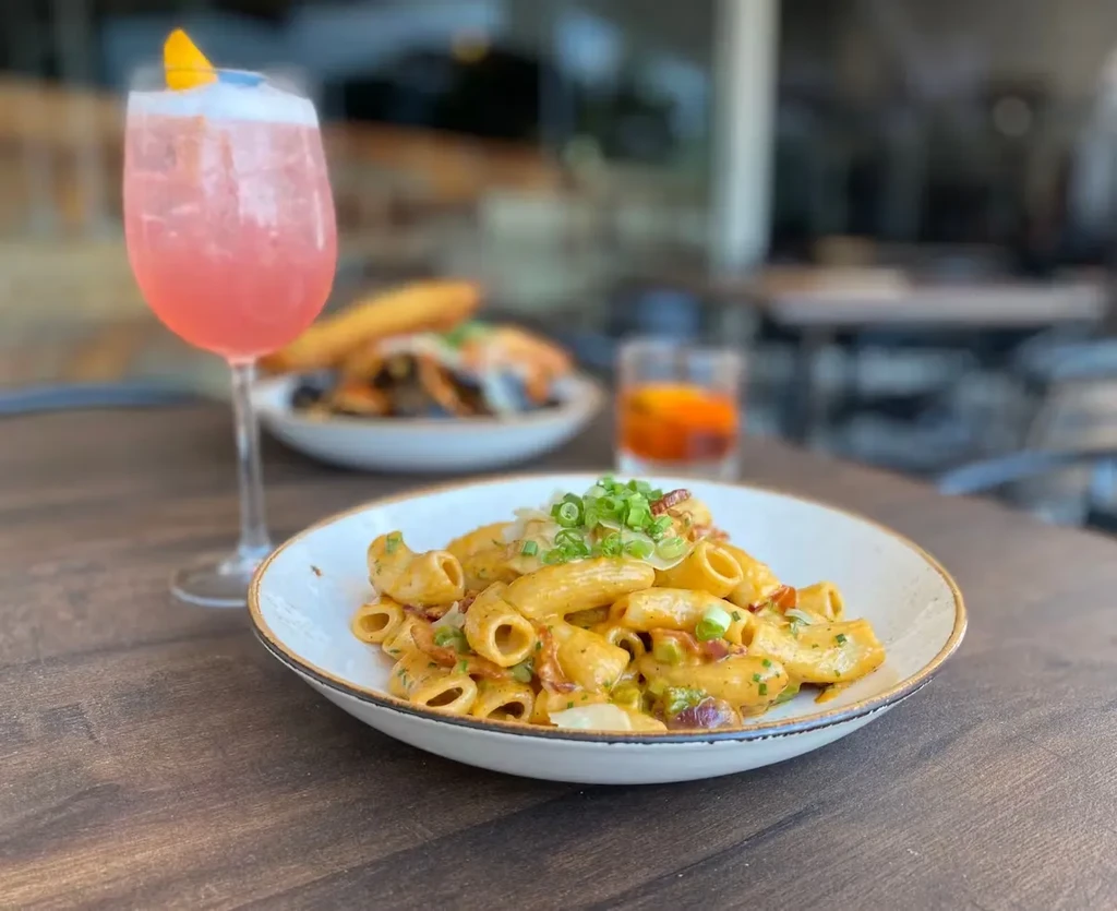 Pasta, pink drink, and food on an outdoor dining table.