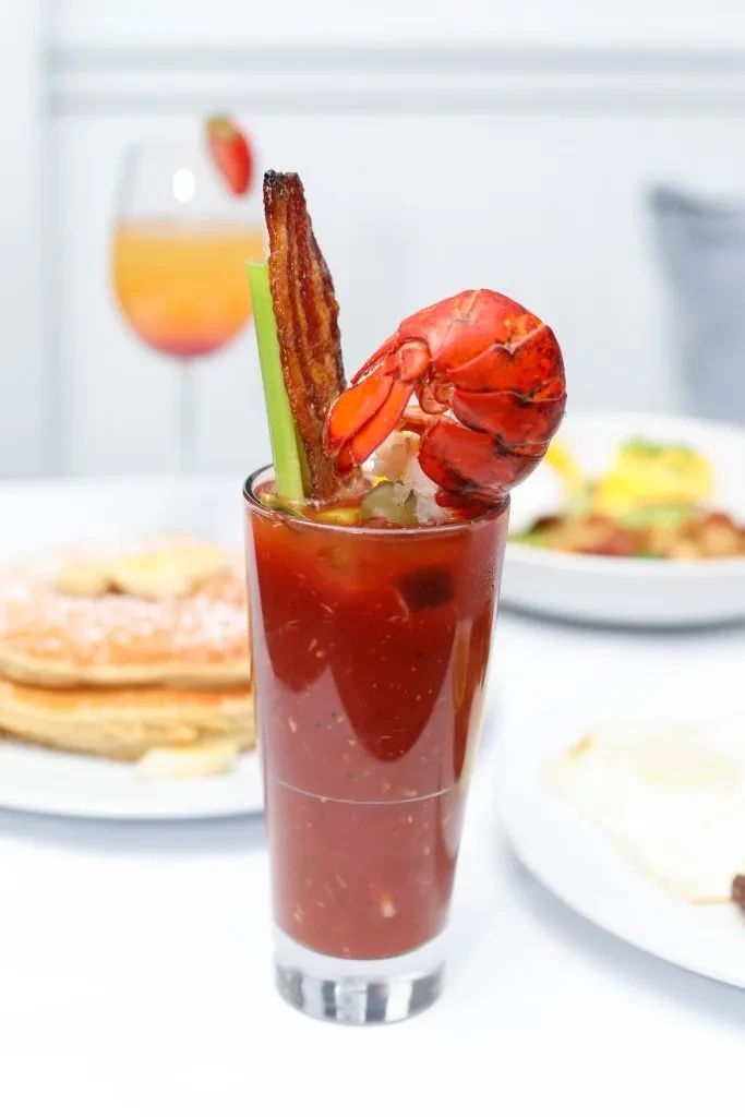 Bloody Mary cocktail garnished with lobster tail, bacon, and celery.
