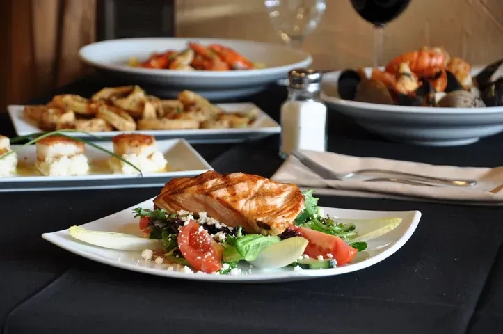 A table set with grilled salmon salad and various appetizers.