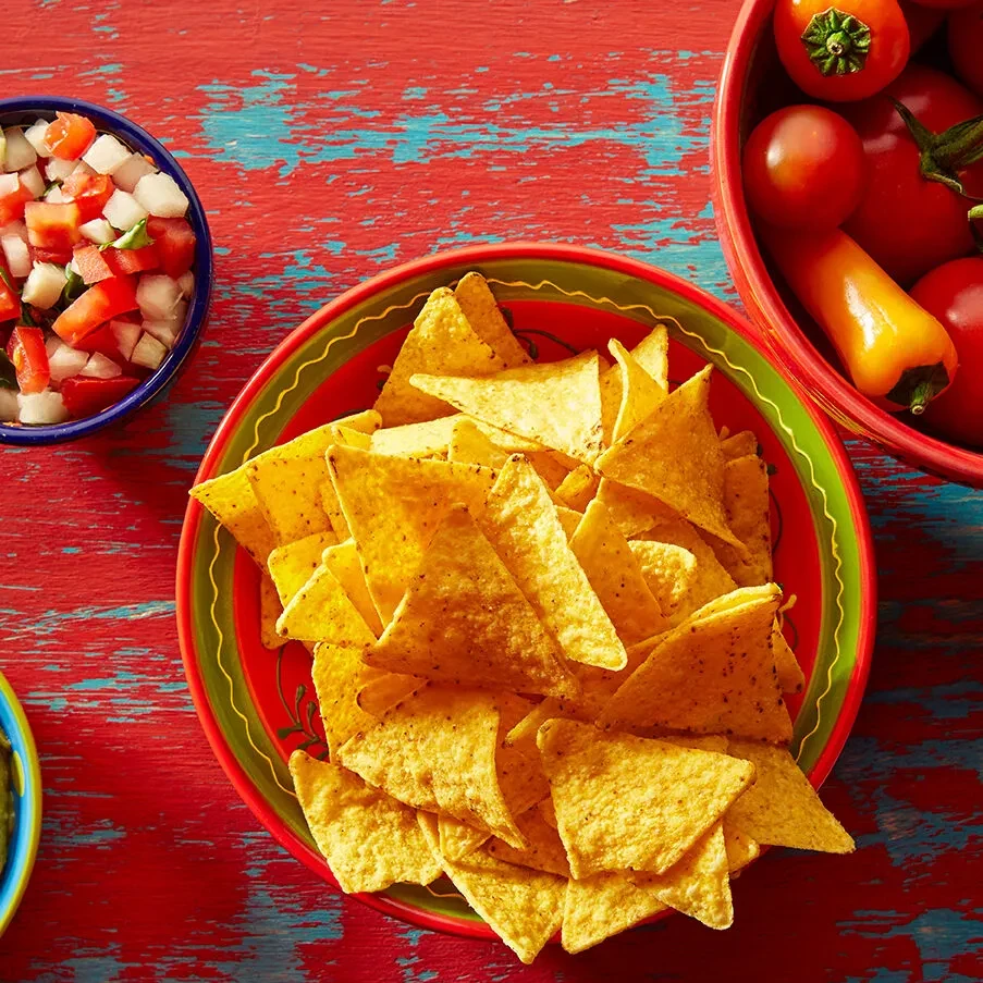 Nachos in a bowl with pico de gallo and cherry tomatoes.